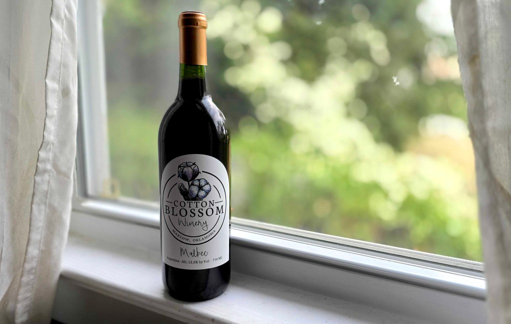 Bottle of red wine from Cottom Blossom Winery sitting on my white window sill.