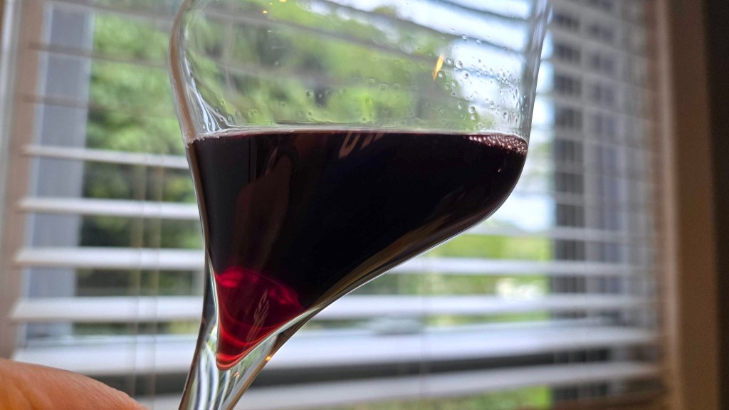 A glass of red wine against a window.
